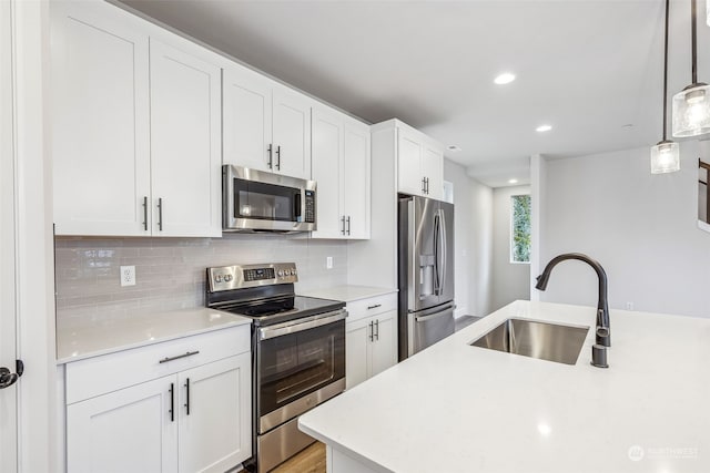 kitchen with appliances with stainless steel finishes, tasteful backsplash, white cabinetry, sink, and hanging light fixtures