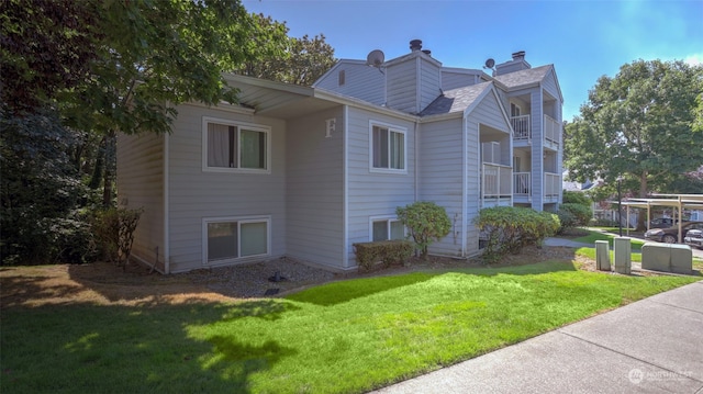 view of side of property with a balcony and a lawn