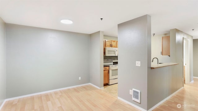 kitchen with light hardwood / wood-style floors, light brown cabinets, and white appliances