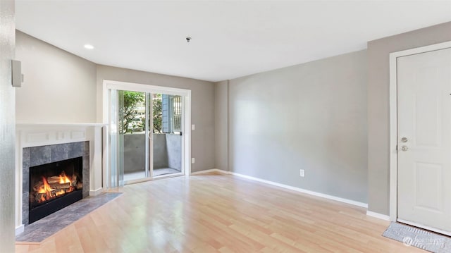 unfurnished living room featuring light hardwood / wood-style floors and a tiled fireplace