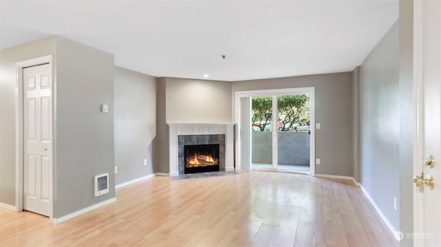 unfurnished living room featuring a tile fireplace and light wood-type flooring