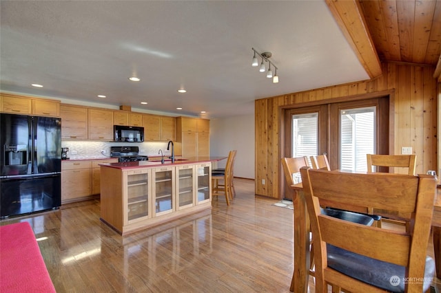 kitchen with a sink, black appliances, an island with sink, light brown cabinetry, and light wood-style floors