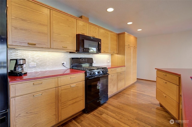 kitchen with light wood-style floors, tasteful backsplash, light brown cabinetry, and black appliances