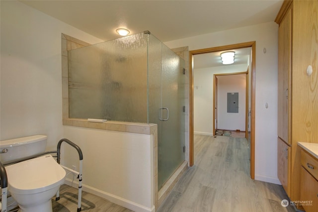 full bath with a shower stall, wood finished floors, vanity, electric panel, and toilet