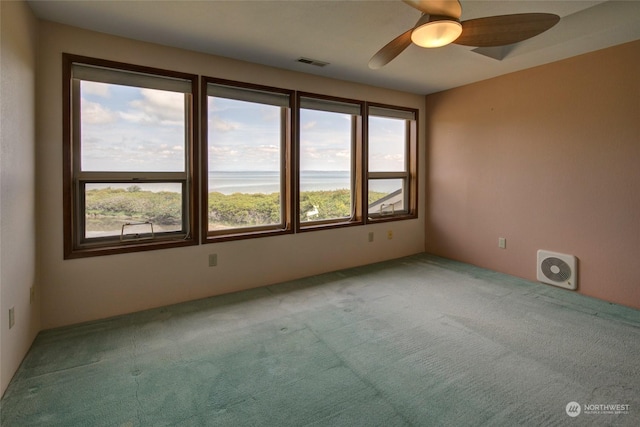 empty room featuring a ceiling fan, visible vents, and carpet