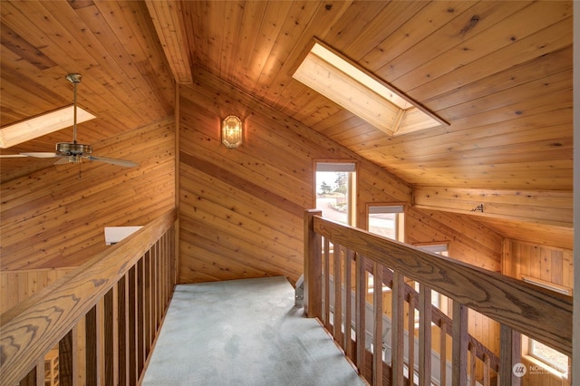 corridor featuring wood ceiling, lofted ceiling with skylight, and an upstairs landing