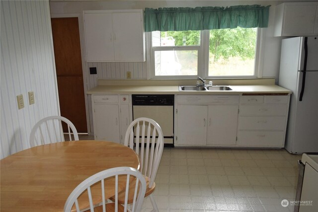 kitchen featuring dishwashing machine, a sink, light countertops, freestanding refrigerator, and light floors