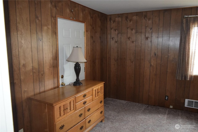 interior space featuring carpet floors, visible vents, and wooden walls