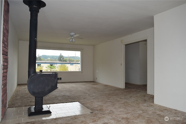 interior space with a wood stove, ceiling fan, and carpet floors