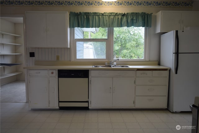 kitchen with light countertops, freestanding refrigerator, white cabinetry, a sink, and dishwasher