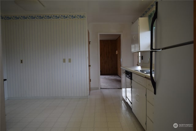 kitchen with white cabinets, black dishwasher, light countertops, freestanding refrigerator, and light floors