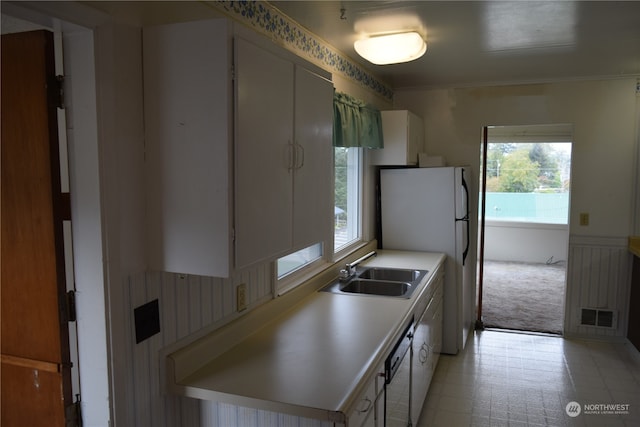 kitchen with light countertops, visible vents, freestanding refrigerator, wainscoting, and a sink