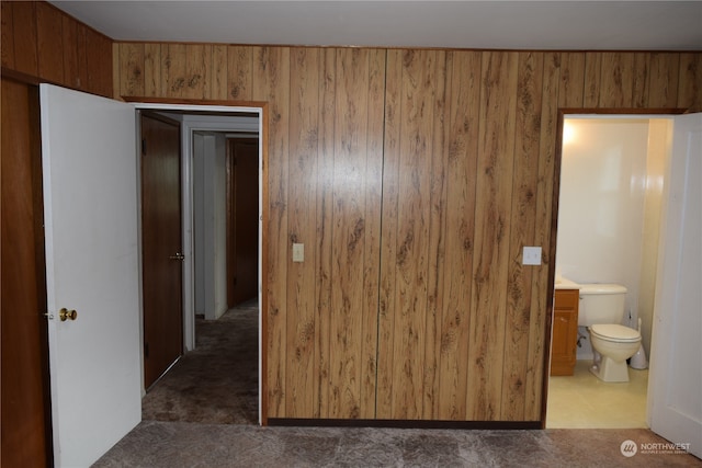 bedroom featuring carpet floors, connected bathroom, and wood walls