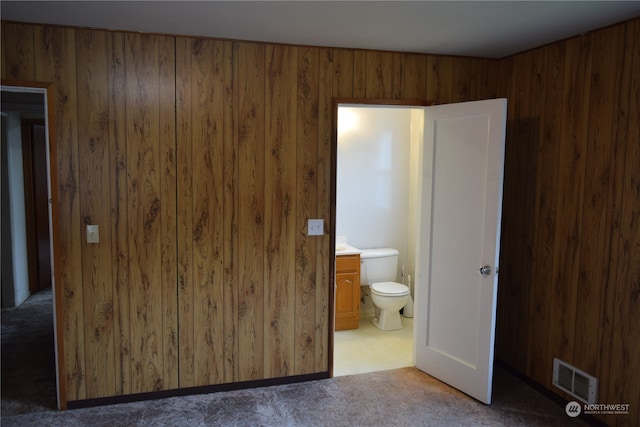 bathroom with toilet, visible vents, and wooden walls