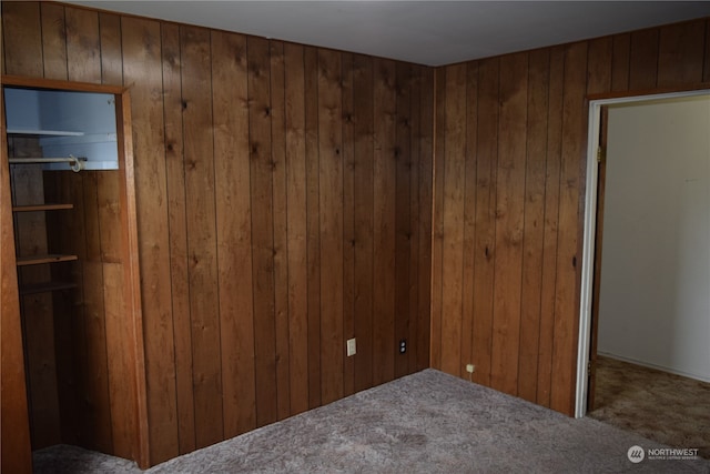 unfurnished bedroom with carpet flooring and wooden walls