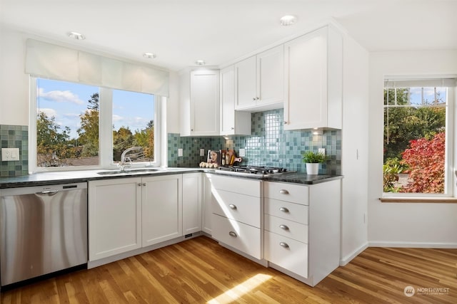 kitchen featuring sink, white cabinets, decorative backsplash, light hardwood / wood-style floors, and stainless steel appliances