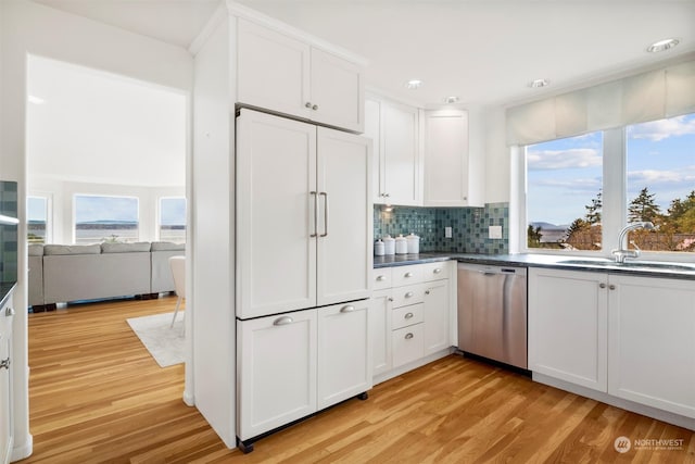 kitchen with tasteful backsplash, light hardwood / wood-style flooring, stainless steel dishwasher, paneled built in fridge, and white cabinets