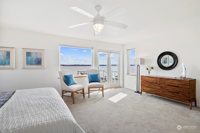 carpeted bedroom with a water view, access to outside, and ceiling fan