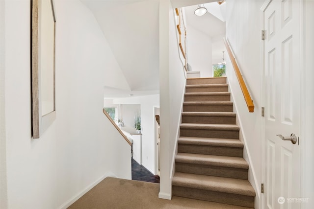 staircase featuring lofted ceiling and carpet floors