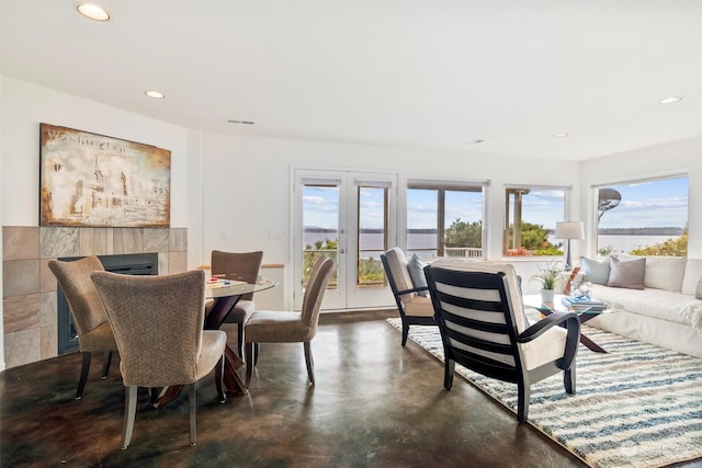 dining room featuring french doors, a water view, and a tiled fireplace