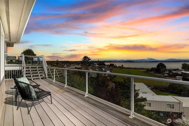 deck at dusk featuring a water view