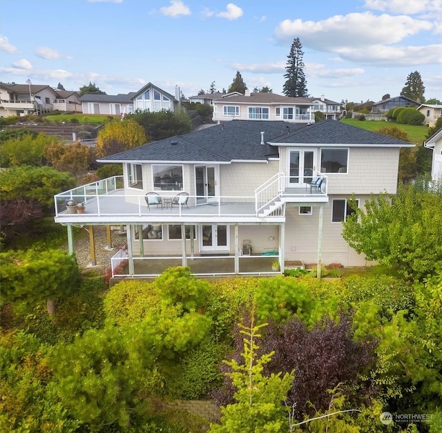 back of house with a wooden deck, a balcony, a patio, and french doors