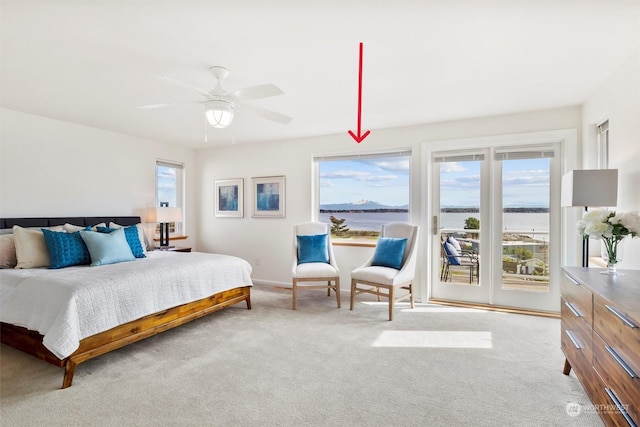 carpeted bedroom featuring multiple windows, access to exterior, ceiling fan, and a water view