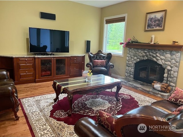 living room featuring light hardwood / wood-style flooring and a stone fireplace