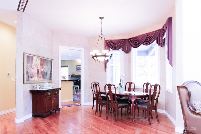 dining area with light hardwood / wood-style flooring and a notable chandelier