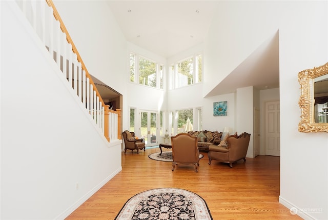 interior space with light wood-type flooring and a towering ceiling