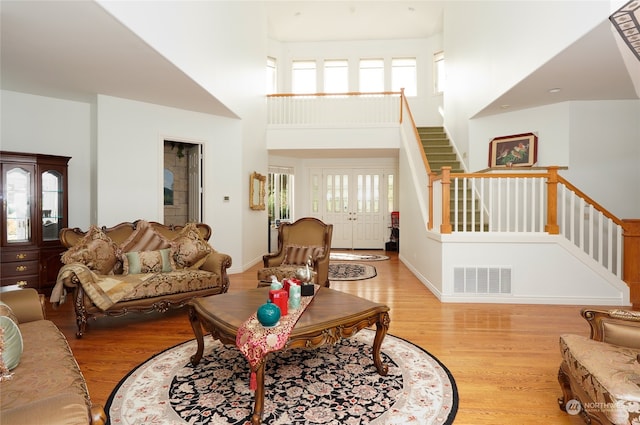 living room with french doors, light hardwood / wood-style floors, and a high ceiling