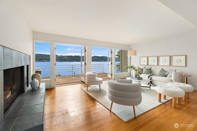 living room featuring hardwood / wood-style floors, a tiled fireplace, and a water view