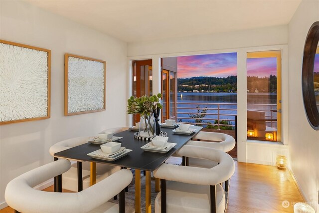 dining room with hardwood / wood-style floors and a water view