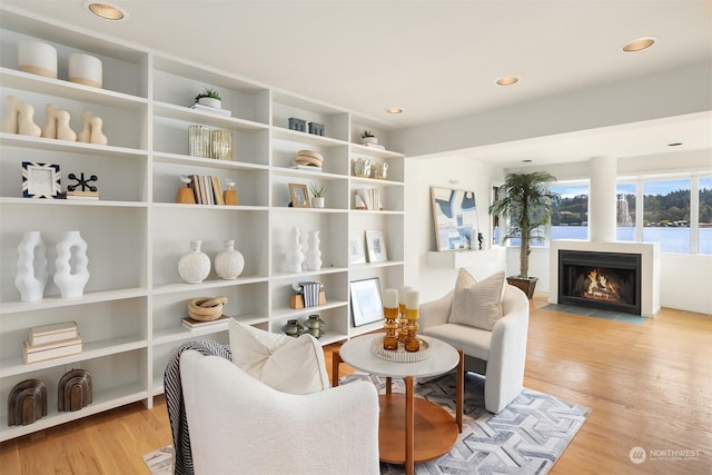 sitting room with a fireplace with flush hearth, recessed lighting, and light wood-style flooring