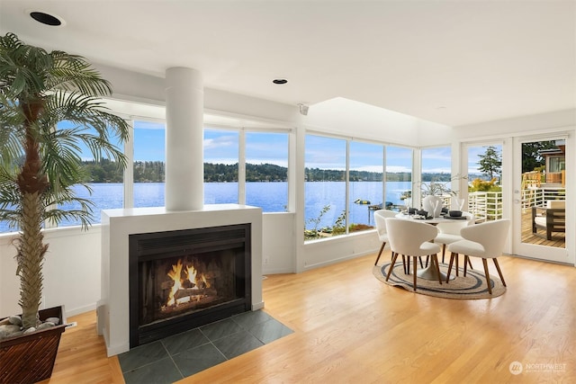 sunroom / solarium with a fireplace with flush hearth and a water view