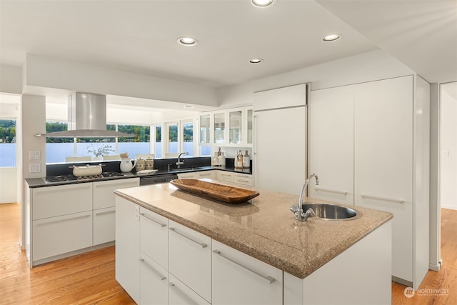 kitchen with sink, island exhaust hood, a kitchen island, white cabinetry, and light wood-type flooring