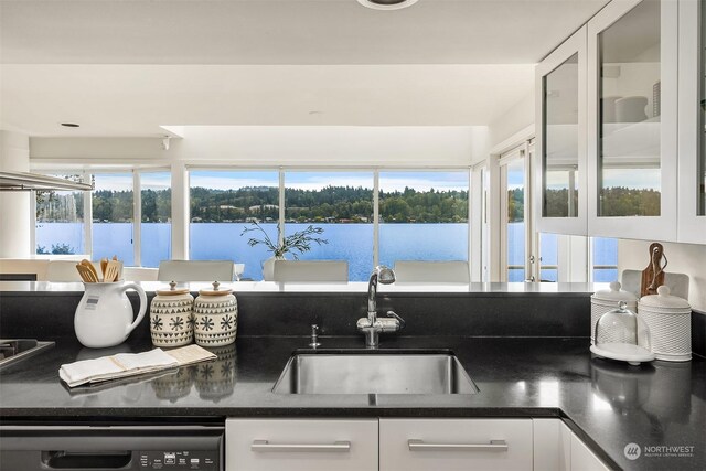 kitchen with dishwasher, white cabinetry, a water view, and sink