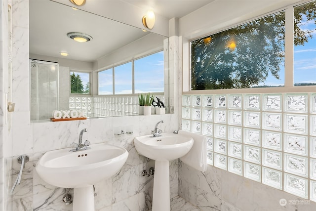 bathroom featuring dual sinks, tile walls, and plenty of natural light