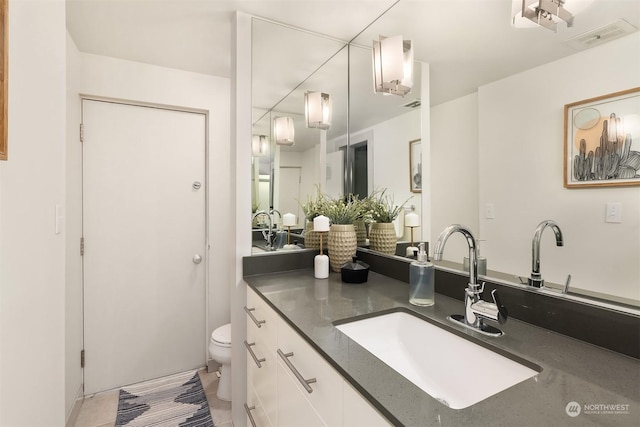 bathroom with toilet, visible vents, and vanity