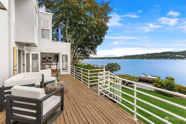 wooden deck featuring an outdoor hangout area, a water view, and a yard