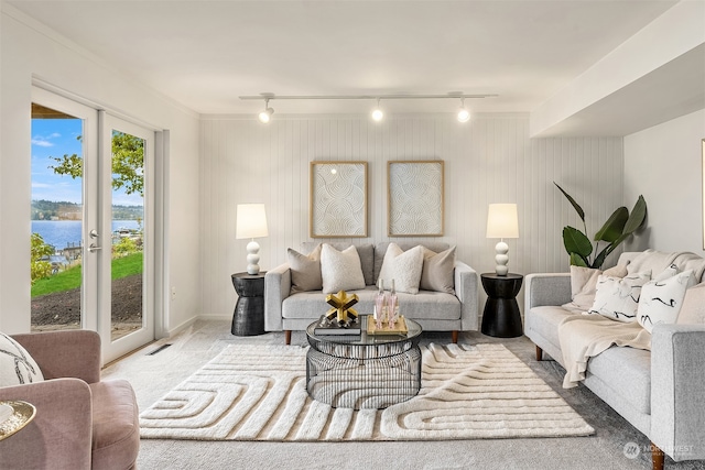 living room featuring carpet floors, track lighting, a water view, and ornamental molding