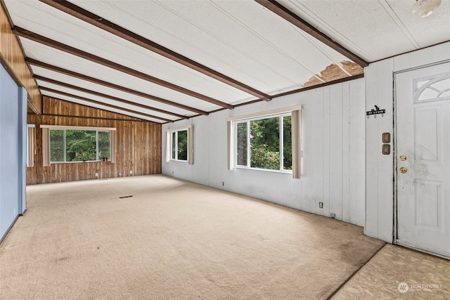 unfurnished living room featuring light carpet and vaulted ceiling with beams