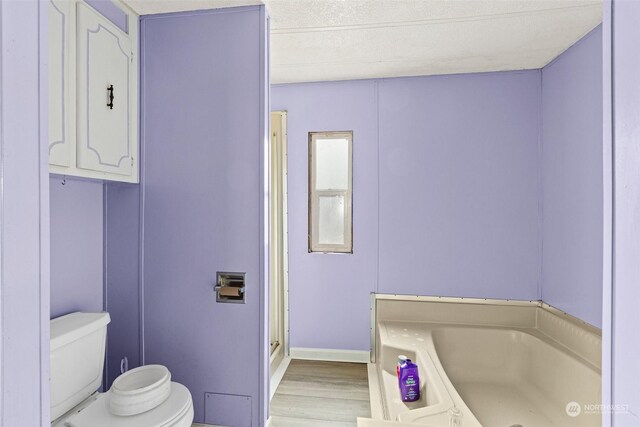 bathroom with toilet, a textured ceiling, shower with separate bathtub, and hardwood / wood-style floors