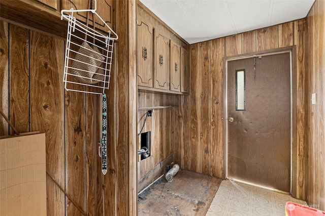 clothes washing area with wooden walls and cabinets