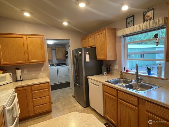 kitchen with vaulted ceiling, independent washer and dryer, stainless steel appliances, and sink