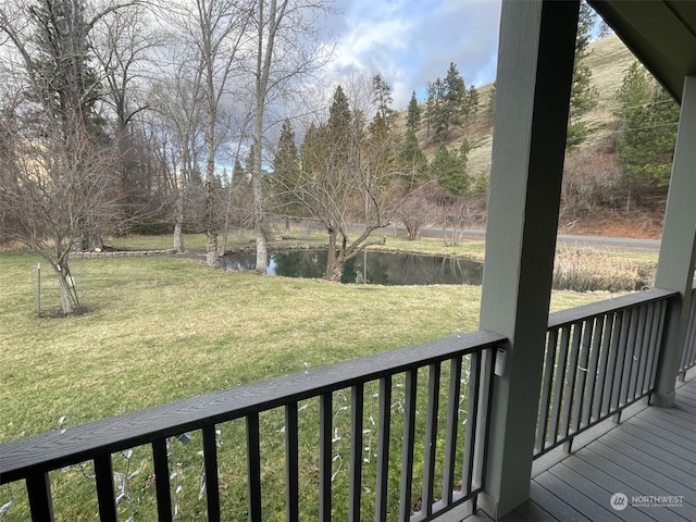 wooden terrace with a water view and a lawn