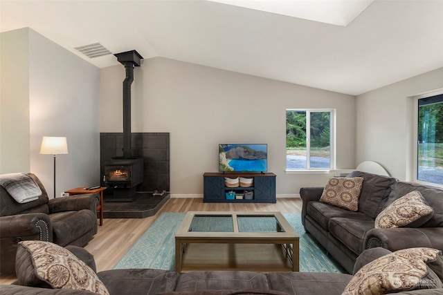 living room with vaulted ceiling, hardwood / wood-style floors, and a wood stove