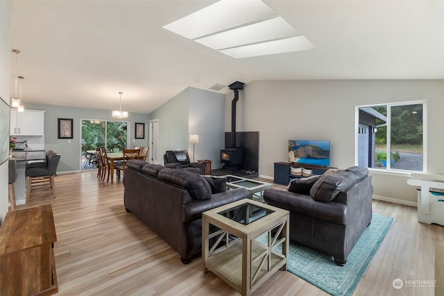living room with vaulted ceiling, light hardwood / wood-style floors, and a wood stove