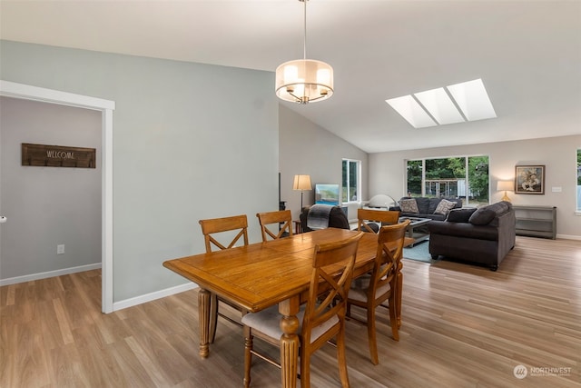 dining room with lofted ceiling with skylight and light hardwood / wood-style flooring