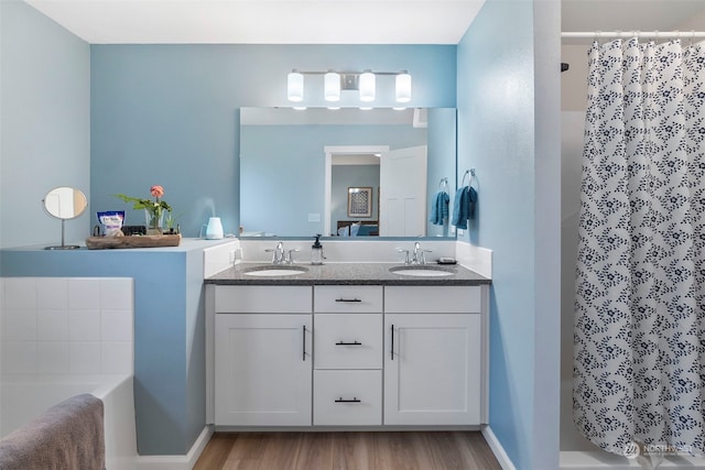 bathroom with dual bowl vanity, hardwood / wood-style floors, and a bath